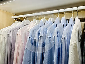 Classy, stylish, colorful men's formal long sleeve shirts neatly arranged and organized in a row on a clothes rack