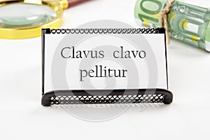 Clavus clavo pellitur. The ancient Greek expression translates as, A wedge is knocked out with a wedge. on a white business card photo