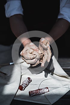 Clay ball. Close-up of female hands knead a ball made of clay to start working on the wheel.