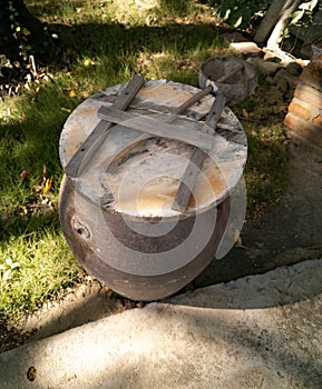 Clay barrel and coconut half ladle near hut on a territory of hotel on a coast of the South China Sea