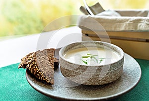 Clay bowl of Finnish salmon cream soup served with leek and croutons on green tablecloth background. Food background