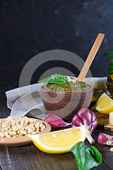 Clay bowl of fresh italian basil pesto sauce and its cooking