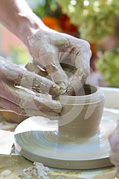 Clay bowl making lesson, muddy fingers shape a clay bowl on a pottery wheel
