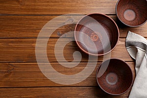 Clay bowls on wooden table, flat lay with space for text. Handmade utensils