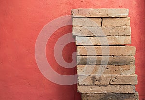 Clay brick stack over red cement wall background