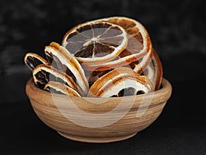clay cup with round dried slices of orange and lemon on a dark background