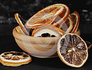 clay cup with round dried slices of orange and lemon on a dark background