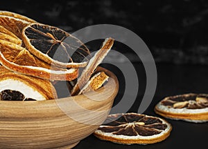 clay cup with round dried slices of orange and lemon on a dark background close-up