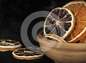 clay cup with round dried slices of orange and lemon on a dark background close-up
