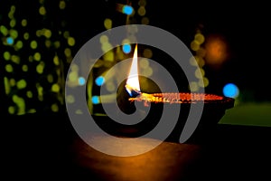 Clay diya candle illuminated in Dipavali, Hindu festival of lights. Traditional oil lamp on dark background