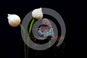 Laughing buddha figurine and white lotus flower buds