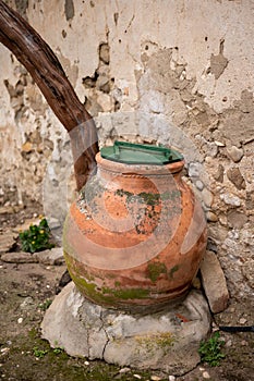 A clay jar with a green lid on an old wall