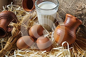 Clay jugs, eggs, glass of milk, on the straw and a burlap.