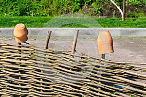 Clay jugs on wooden wicker fence. Traditional ukrainian rural decor