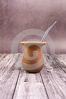 Clay mate calabash with bombilla on grey wood background