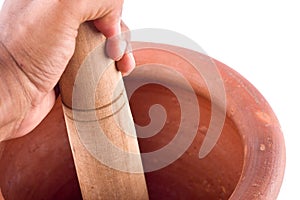 Clay mortar and wood pestle is used to mix the ingredient with male hand on white background cooking kitchenware object isolated