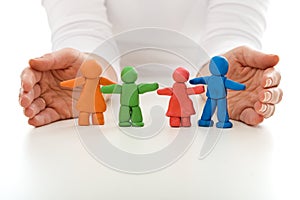 Clay people family protected by woman hands photo