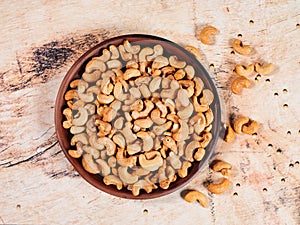 Clay plate with cashew nuts on a wooden background