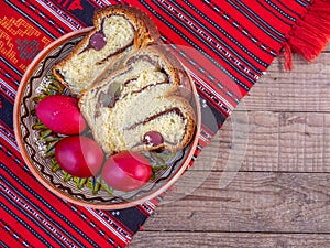 Clay plate with slices of traditional easter sweet bread or cozonac and red painted eggs, romanian easter tradition