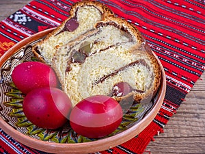 Clay plate with slices of traditional easter sweet bread or cozonac and red painted eggs, romanian tradition