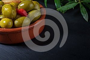 Clay pot with artisan olives preserved in extra virgin olive oil, vinegar, spices with red peppers and garlic.