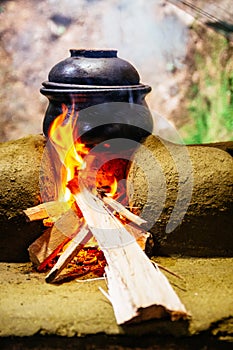 A clay pot cooking and heated over a wood fired stove made out o