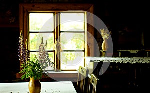 Clay pot and flower bouquet at the table near the window. Vintage retro still life photo. Village house interior concept