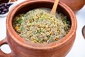 Clay pot with peruvian Arroz con Pollo, which is made of rice, chicken parts, peas, corn, aji hot pepper and cilantro.