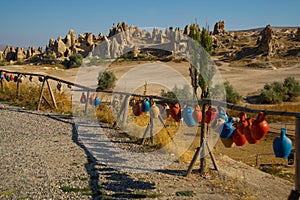 Clay pots with inscriptions are on the fence.View of the rocks in the valley near the city of Goreme in Cappadocia, Turkey