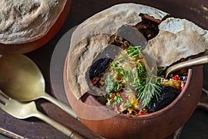 Clay pots with stewed vegetables on a wooden table, closeup. Stewing food in earthenware is considered healthy