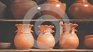 Clay pottery on wooden shelf in vintage tone style