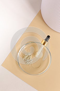 Clay powder and water in glass jar near pipette on beige and white background.