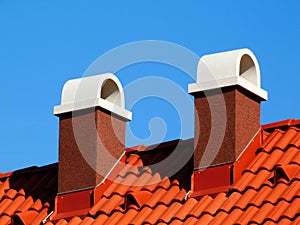 Clay tile roof detail with stucco finished chimney. blue sky