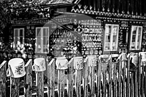 Clay vintage pot on fence in front of wooden cottage