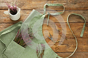 Clean apron with beautiful flowers on wooden table, flat lay