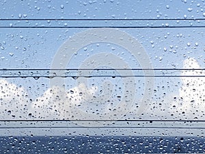 Clean background view of water drops on glass over a blue sky. Rain water drops on glass with tropical blue sky background with