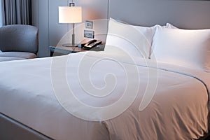 Clean Bedding sheets and pillow on natural wall room background. White bedding and pillow in hotel room. White pillows on bed.