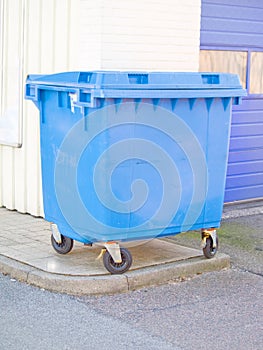 Clean blue plastic rubbish bin in urban area