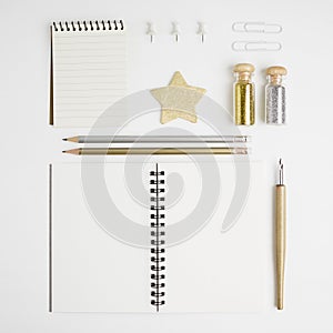 Clean and bright stationary mock-up: notebooks, foutain pen, pencils, gold and silver glitters, pins and stars on white background