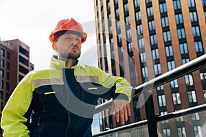 A clean builder shows sincere emotions of indignation. Man in special clothes and helmet shows hostility