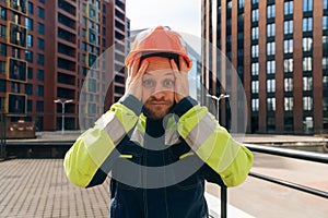 A clean builder shows sincere emotions of indignation. Man in special clothes and helmet shows hostility