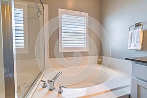 Clean built in round bathtub beside glass wall of shower stall of home bathroom