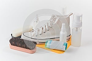 Clean canvas sneaker, brush, sponge and various detergents on white background