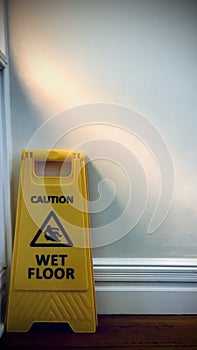 Clean Caution Wet Floor sign is behind the door. Vertical photo image.
