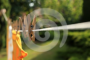Clean clothes drying outdoors during sunny day, focus on laundry line with wooden clothespins