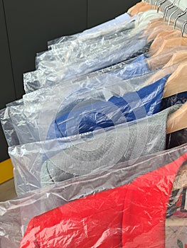 Clean clothes on hangers in dry-cleaning bags closeup