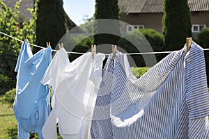 Clean clothes hanging on washing line in garden, closeup. Drying laundry