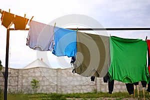 clean colorful clothes t shirts hanging to dry on a laundry line outdoors, housework.