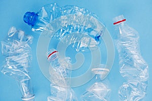 Clean crumpled plastic water bottles ready for recycling isolated on blue background, top view, flat lay