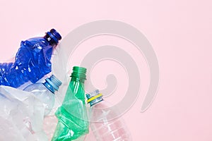 Clean crumpled plastic water bottles and white plastic bag ready for recycling isolated on pink background